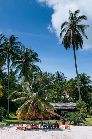 NOV 11, 2013 Samui, Thailand - Local Thai tourists sitting on colourful beach beds under coconut tree on Koh Tean near Koh Samui. Thailand summer vacation on small islandのeditorial素材