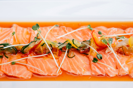 Fresh salmon tataki with hamemade ponzu sauce and Kaiware sprouts in white plate close up shotの写真素材