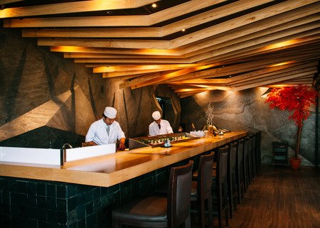 JUN 10, 2013 Bangkok, Thailand - Modern Vibrant Japanese Sushi bar interior, Wood decorated ceiling with warm lighting, Sushi chef working behind the barのeditorial素材