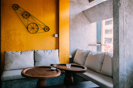 JAN 10, 2013 Bangkok, Thailand - Contemporary sofa couch and old vintage dinner table and with Bright yellow wall natural lightのeditorial素材