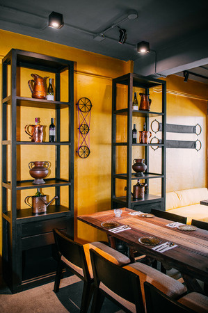 JAN 10, 2013 Bangkok, Thailand - Contemporary wooden dinner table and chair with Bright yellow wall and vintage wood shelves warm tone lightのeditorial素材