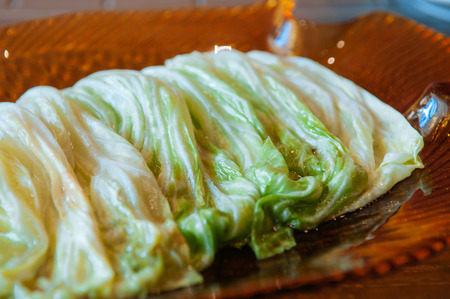 Thai food on dinner table, stir fried fresh cabbage with fish sauce in vinatge coloured glass plate on wood table - close up shotの写真素材
