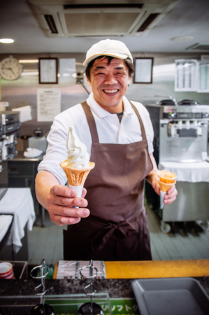 MAY 28, 2013 Nagano, Japan - Fresh icy cold creamy rich soft serve Wasabi ice cream cone - Japanese Wasabi ice cream in a smiling man hand - close up shotのeditorial素材