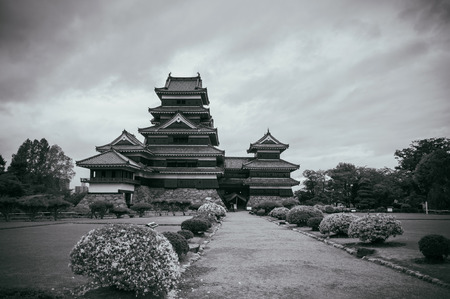 Matsumoto Castle Japan premier historic castle - Black crow castle - Nagano, Japan on cloudy day in summer with grass lawn flower bushes black and white imageのeditorial素材