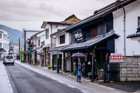MAY 29, 2013 Matsumoto, JAPAN - Old Japanese Edo architecture building with ceramic tiles roof  in Nakamachi dori street area with local people under umbrella on rainy dayのeditorial素材