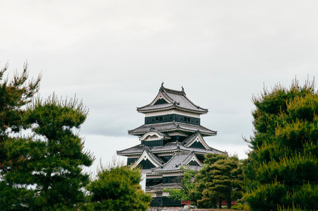 Matsumoto Castle Japan premier historic castle - Black crow castle - Nagano, Japan on cloudy day in summer with green pine treeのeditorial素材