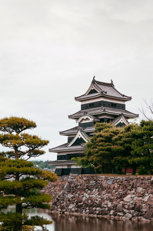 Matsumoto Castle Japan premier historic castle - Black crow castle - Nagano, Japan on cloudy day in summer with pine tree and canalのeditorial素材