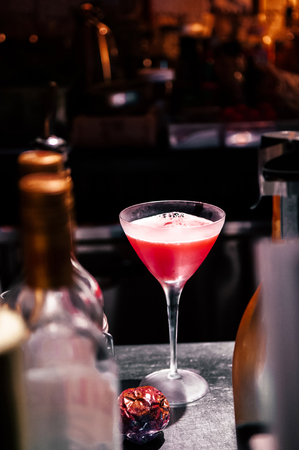 Beautiful Red passion fruit cocktail in martini glass with dark background on bar counterの写真素材