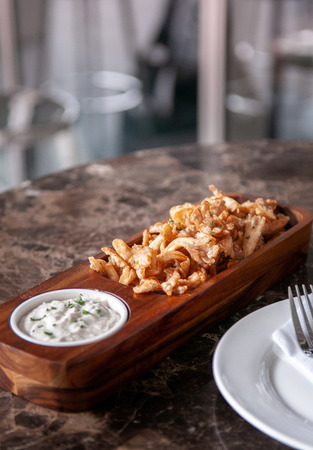 Crunchy deep fried calamari with Tartar sauce in hard wood plate on marble table, close up shotの写真素材
