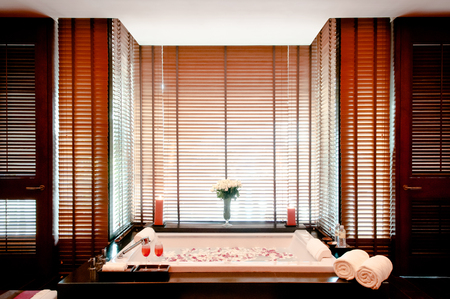 JAN 8, 2013 Bangkok, Thailand - Asian Thai spa rose flower bath with candle, and glass of Shirley Temple cocktail warm atmosphere with slightly natural light through bamboo venetian blindsのeditorial素材
