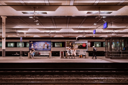 SEP 28, 2013 Bern, Switzerland - Bern city train station platform with old and young local passengers waiting for train, warm lighting urban sceneのeditorial素材