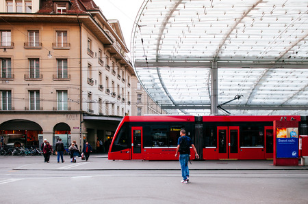 SEP 28, 2013 Bern, Switzerland - Modern architecture tram and bus stop in the city center, many people walking accross the street. Modern unique public transport stop is covered by large glass roofのeditorial素材