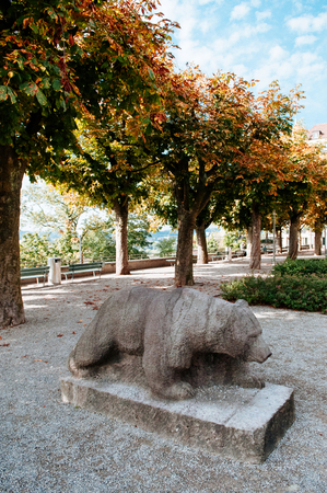 Bern, Switzerland - Carved stone bear statue icon simbol of Bern city at Evangelical church Munsterplattform garden with big tree in early autumn seasonの写真素材