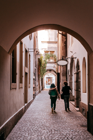 SEP 27, 2013 Bern, Switzerland - Tourists walking on small backstreet alley under arch arcade with warm evening light in old town district of Bernの写真素材