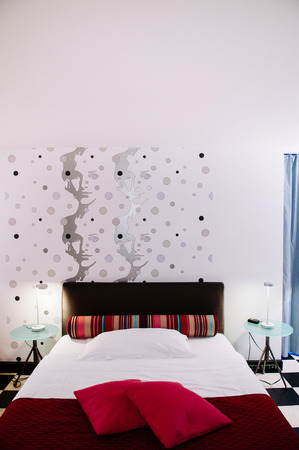 SEP 28, 2013 Bern, Switzerland - Modern vibrant colourful bedroom interior with red armchair, fabric...