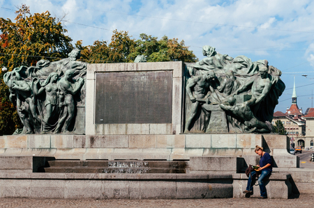 SEP 28, 2013 Bern, Switzerland - People sit at old vintage bronze sculpture Welttelegrafen Denkmal monument in  Famous old town area near Bern History museumのeditorial素材