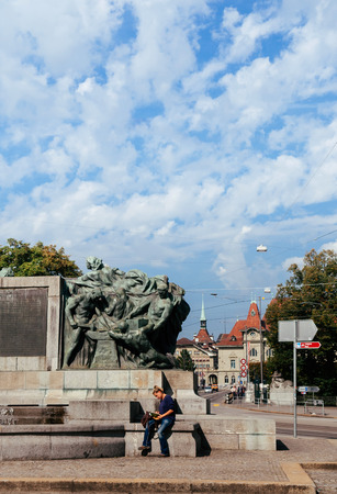 SEP 28, 2013 Bern, Switzerland - People sit at old vintage bronze sculpture Welttelegrafen Denkmal monument in  Famous old town area near Bern History museumのeditorial素材