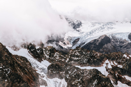 Rock cliff  rise high behind cloud and deep snow mountain valley of Titlis in Engelberg, Switzerland
