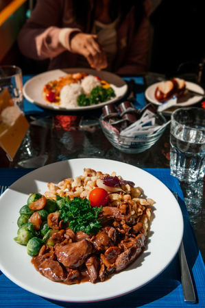 Swiss Gourmet Venison goulash Emince Zurichoise, grill Brussel sprouts and garnish in white plate under sunlight on dinner tableの写真素材