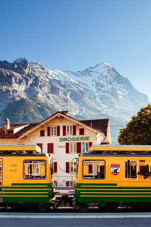 SEP 24,2013 Lauterbrunnen, Switzerland - Yellow Grindelwald train at Kleine Scheidegg station with Tschuggen peak on background, base station for Jungfraujochのeditorial素材