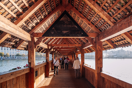 SEP 24, 2013 Luzern, Switzerland - Tourist walking and interior wood structure of Lucerne medieval Chapel Bridge in bright warm evening sunlightのeditorial素材