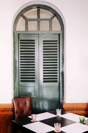 Old vintage  house interior with retro chessboard pattern dinner table, leather chair and olive green wooden door. Colonial building interiorの写真素材