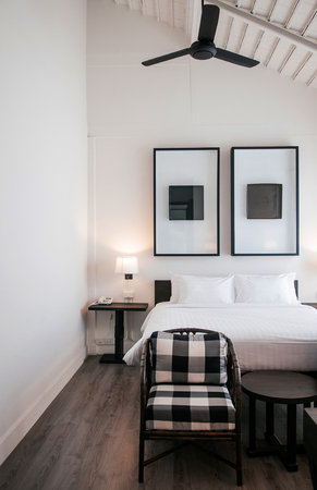 FEB 10, 2014 Chiang Mai, THAILAND - Asian contemporary hotel bedroom with wooden bed, white sheet, pillows, lamp, old wood table, retro rattan chairs and modern wall picture frameのeditorial素材