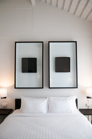 FEB 10, 2014 Chiang Mai, THAILAND - Asian contemporary hotel bedroom with wooden bed, white sheet, pillows, lamp, old wood table and modern wall picture frameのeditorial素材