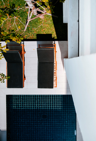 FEB 10, 2014 Chiang Mai, THAILAND - Outdoor hotel furniture black modern sunbeds by the dark blue pool and tropical garden, top viewのeditorial素材