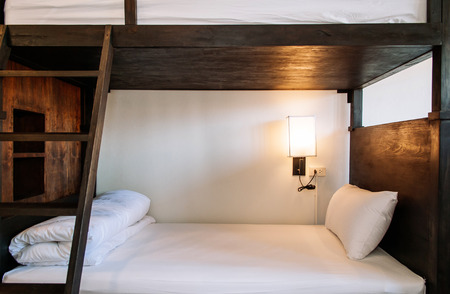 Hostel dormitory bunk beds arranged in room, backpacker hostel furnished with wooden dormitory style bunk beds and whit clean linens.の写真素材