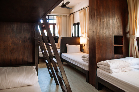 FEB 12, Chiang Mai, THAILAND - Hostel dormitory bunk beds arranged in room, backpacker hostel furnished with wooden dormitory style bunk beds and whit clean linens.のeditorial素材