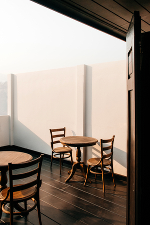 Vintage old wooden round dining table and chair at outdoor balcony under warm evening lightの写真素材
