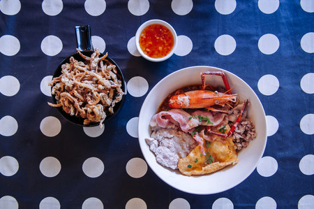 Thai seafood noodle with pork, bacon, river prawn, crispy fried mushroom and condiments set on polka dot tableclothの写真素材