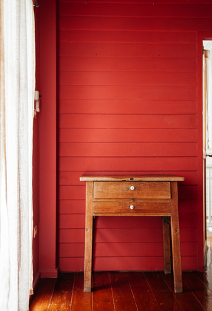 AUG 4, 2014 Bangkok, Thailand - Oriental Thai-Chinese vintage wooden drawers desk in old house with red wood wall and brown wood floor with natural light from windowのeditorial素材