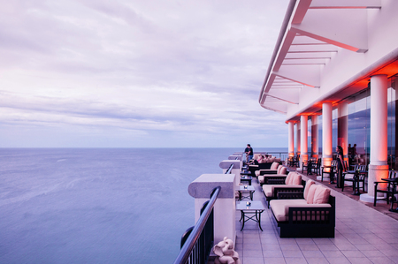 AUG 6, 2014 Hua Hin - Thailand - Sea view terrace or outdoor sunset lounge deck with contemporary sofa couches and some guests at luxury hotel in beautiful evening on cloudy day.のeditorial素材