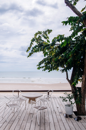 AUG 7, 2014 Hua Hin, Thailand - Tropical vacation. Seaview wooden balcony with well design chair and table under big tree on cloudy day in rainy seasonのeditorial素材
