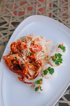 Som Tum - Thai spicy papaya salad with deep fried soft shell crab and rice noodle in white plate. Top viewの写真素材