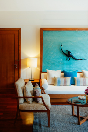 AUG 7, 2014 Hua Hin, THAILAND - Asian luxury style wood floor hotel living room with contemporary furnitures, chairs, tables , colourful pillows and Thai style wall decorationのeditorial素材