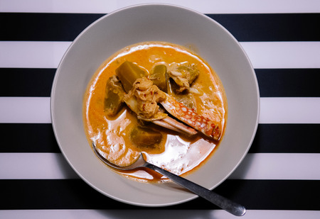 Delicious Thai coconut milk red curry with blue swimmer crab legs and pumpkin, top view with black and white strips background.の写真素材