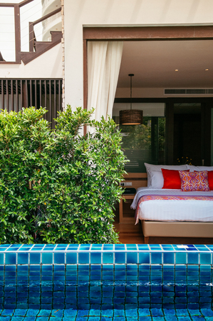 AUG 6, 2014 Hua Hin, THAILAND - Asian Thai tropical garden pool side hotel room with bed and colourful pillows. Rattan pedant lamps hanging from ceiling.のeditorial素材