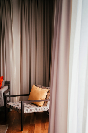 Colourful modern furniture, wood chairs in Asian style hotel room with yellow pillow, natural light through curtainの写真素材
