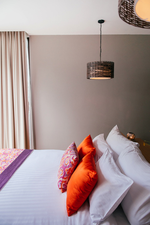AUG 6, 2014 Hua Hin, THAILAND - Asian Thai tropical hotel room with bed and colourful pillows, rattan pedant lampsのeditorial素材