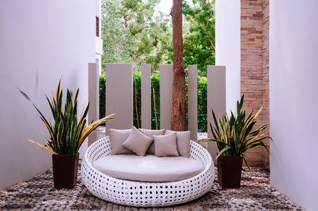 Modern furniture, outdoor rattan sofa couch and plant pots with garden scene on backgroundの写真素材