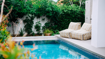 AUG 4, 2014 Hua Hin, THAILAND - Tropical garden hotel swimming pool with modern strip pattern bean...