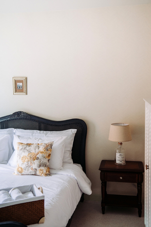 Vintage cozy hotel room with bed, white lamp, pillows, classic wooden bed, side table. Vintage country home decorationの写真素材