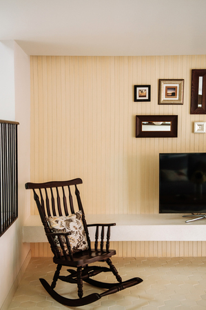 AUG 4, 2014 Hua Hin, THAILAND - Asian style living room with beige colour wall, vintage wooden rocking chair and picture framesのeditorial素材