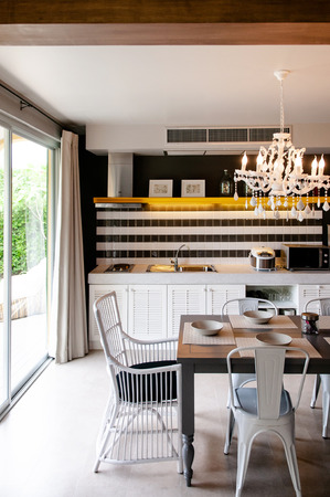 AUG 4, 2014 Hua Hin, THAILAND - Light tone furniture in dining area with white chandelier and pantry kitchen. Cozy contemporary home interior furnituresのeditorial素材