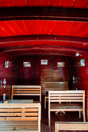 FEB 26, 2014 Dalat, Vietnam - Antique old classic train car wooden interior with red colour became luch room with wood bench seats and tablesのeditorial素材