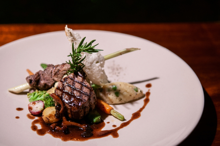 Beef sirloin steak with red wine gravy mushroom, vegetable and roasted potato in white plate - close up food shotの写真素材