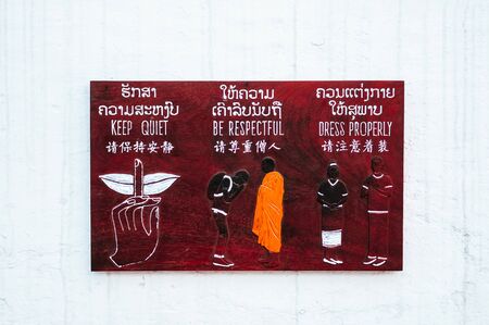 Rules information on wooden sign on white temple wall,  Be respectful. Dress properly, and be quiet